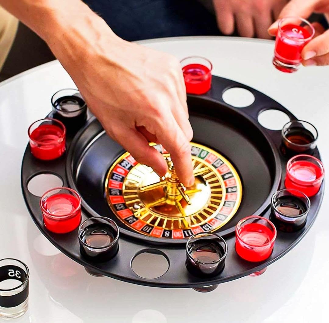 Roulette-themed drinking game with red and black shot glasses on a white surface.