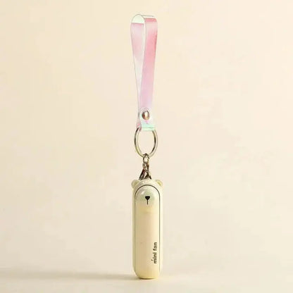 Small handheld fan with a keychain strap on a beige background
