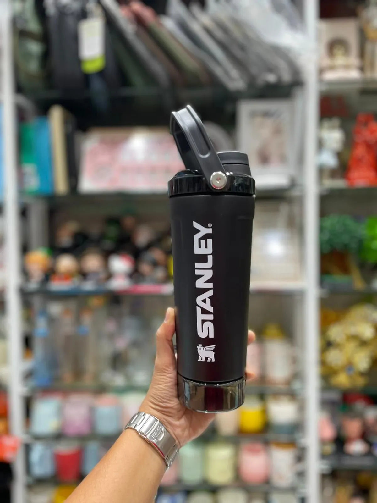 Black Stanley Protein shaker water bottle on a gray surface with a white background