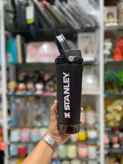 Black Stanley Protein shaker water bottle on a gray surface with a white background