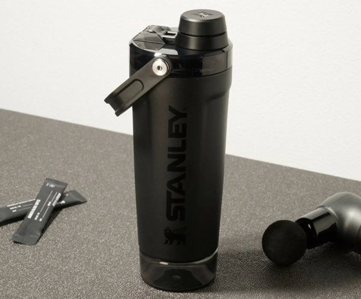 Black Stanley Protein shaker water bottle on a gray surface with a white background