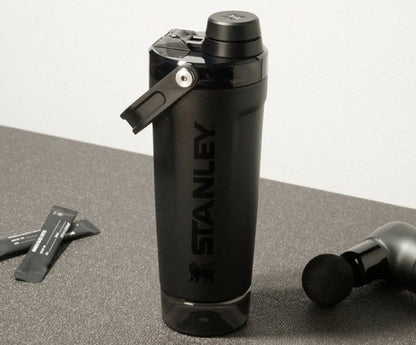 Black Stanley Protein shaker water bottle on a gray surface with a white background